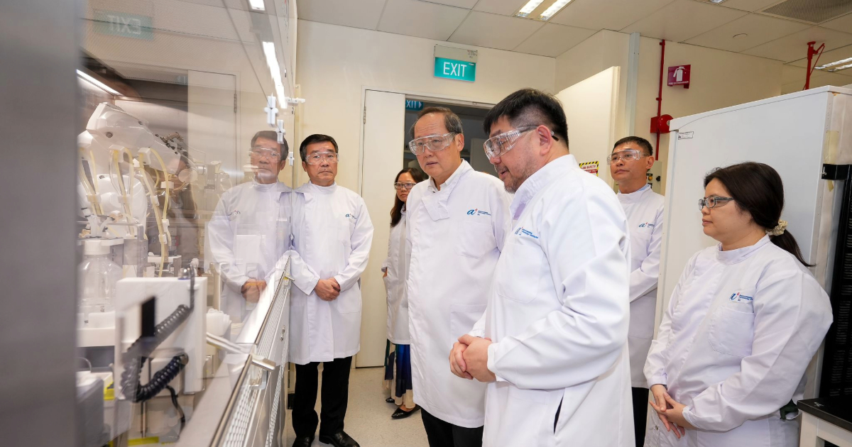Prof Andre Choo (Deputy Executive Director, BTI) demonstrates an automated process to Dr Tan Lee Seng (Minister for Manpower and Second Minister for Trade and Industry) in a lab, with Prof Koh Boon Tong (Executive Director, BTI) and others observing