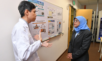 President Halimah speaking to Associate Professor Melvin Leow- Deputy Director of CNRC
